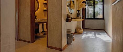 A modern bathroom with a large mirror, wooden shelves, and a window providing natural light.