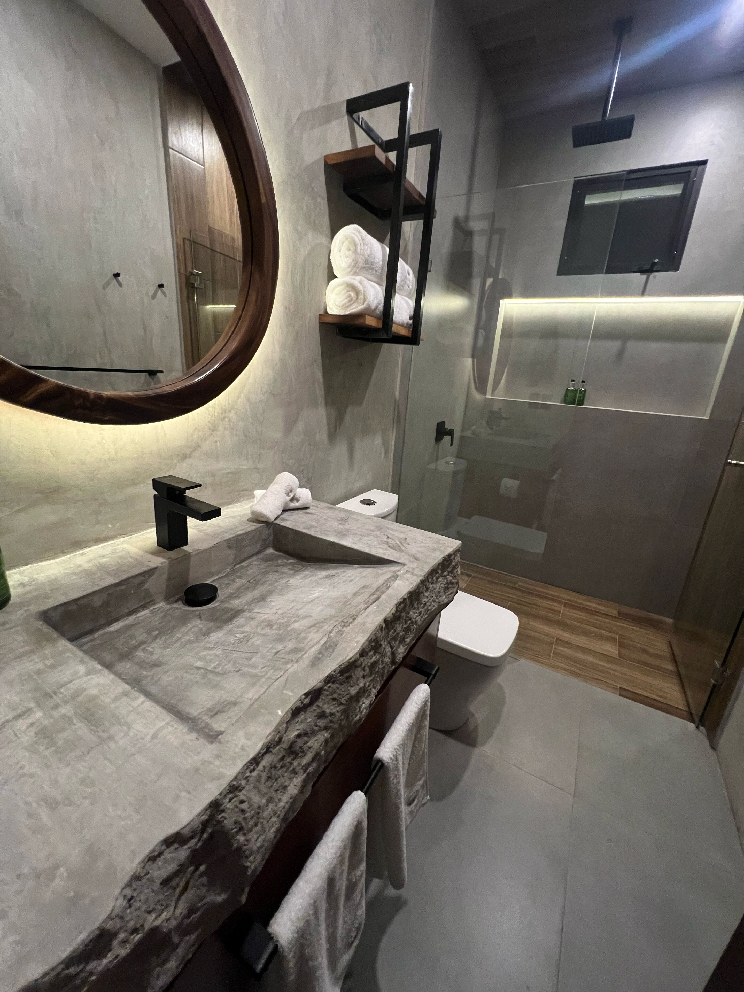 A modern bathroom with a granite sink, a large mirror, and a towel rack.