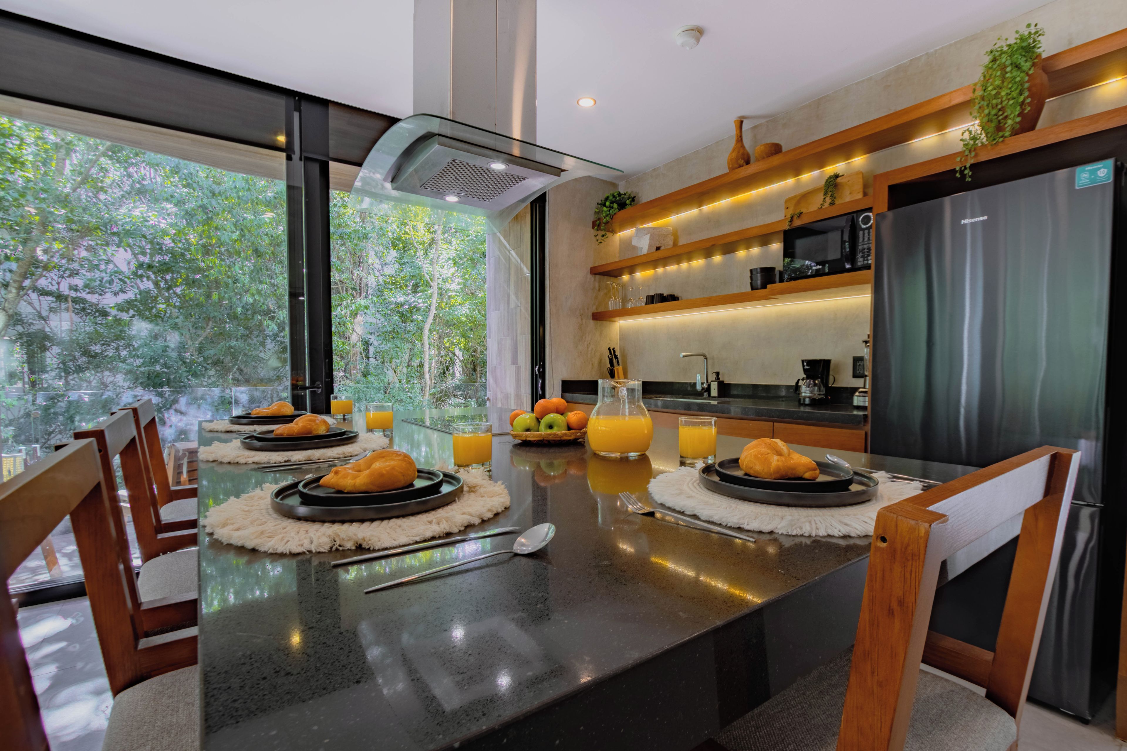 Una cocina moderna con una isla central, sillas de madera y vistas a zonas verdes.