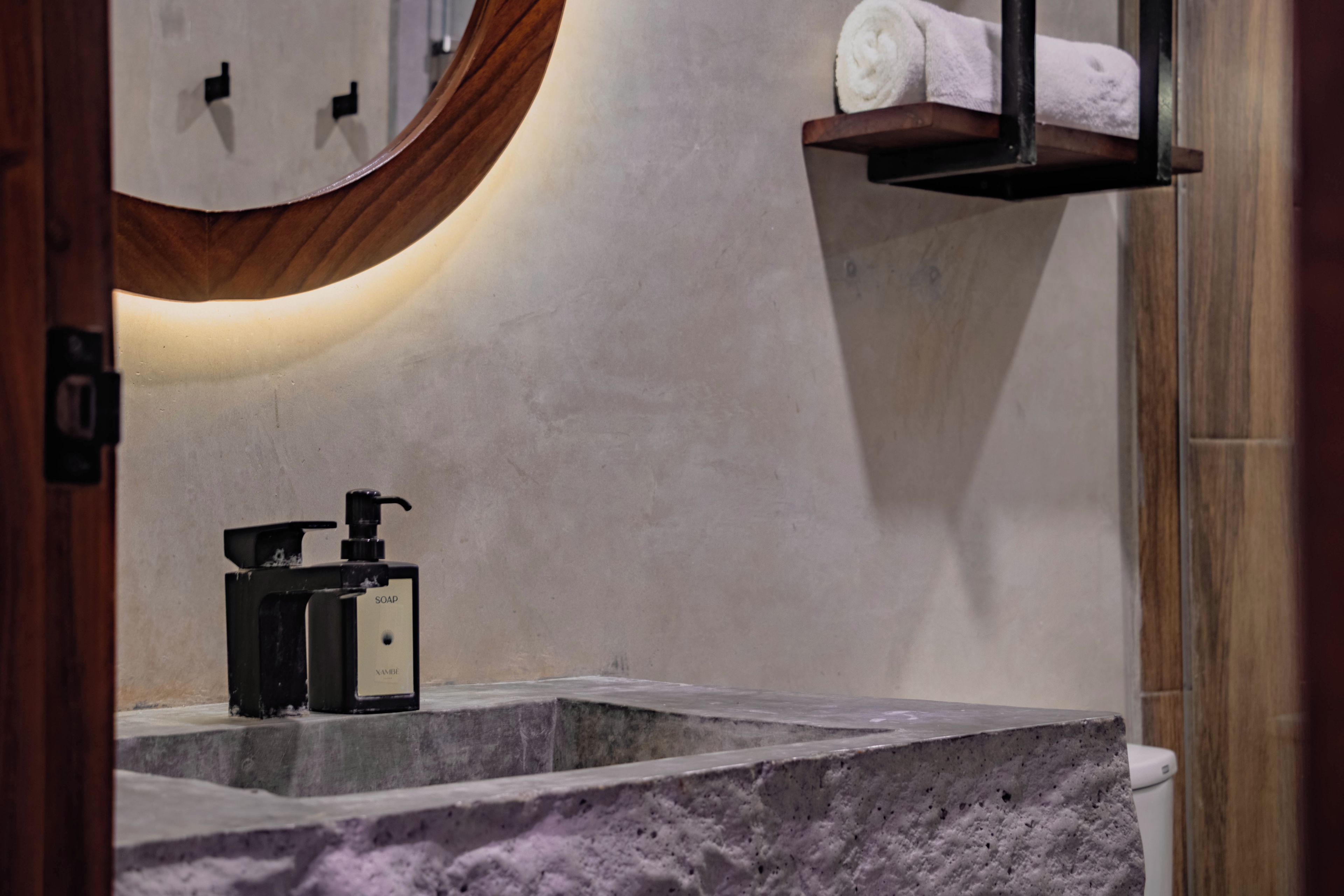 A bathroom with a marble sink, a soap dispenser, and a towel rack.
