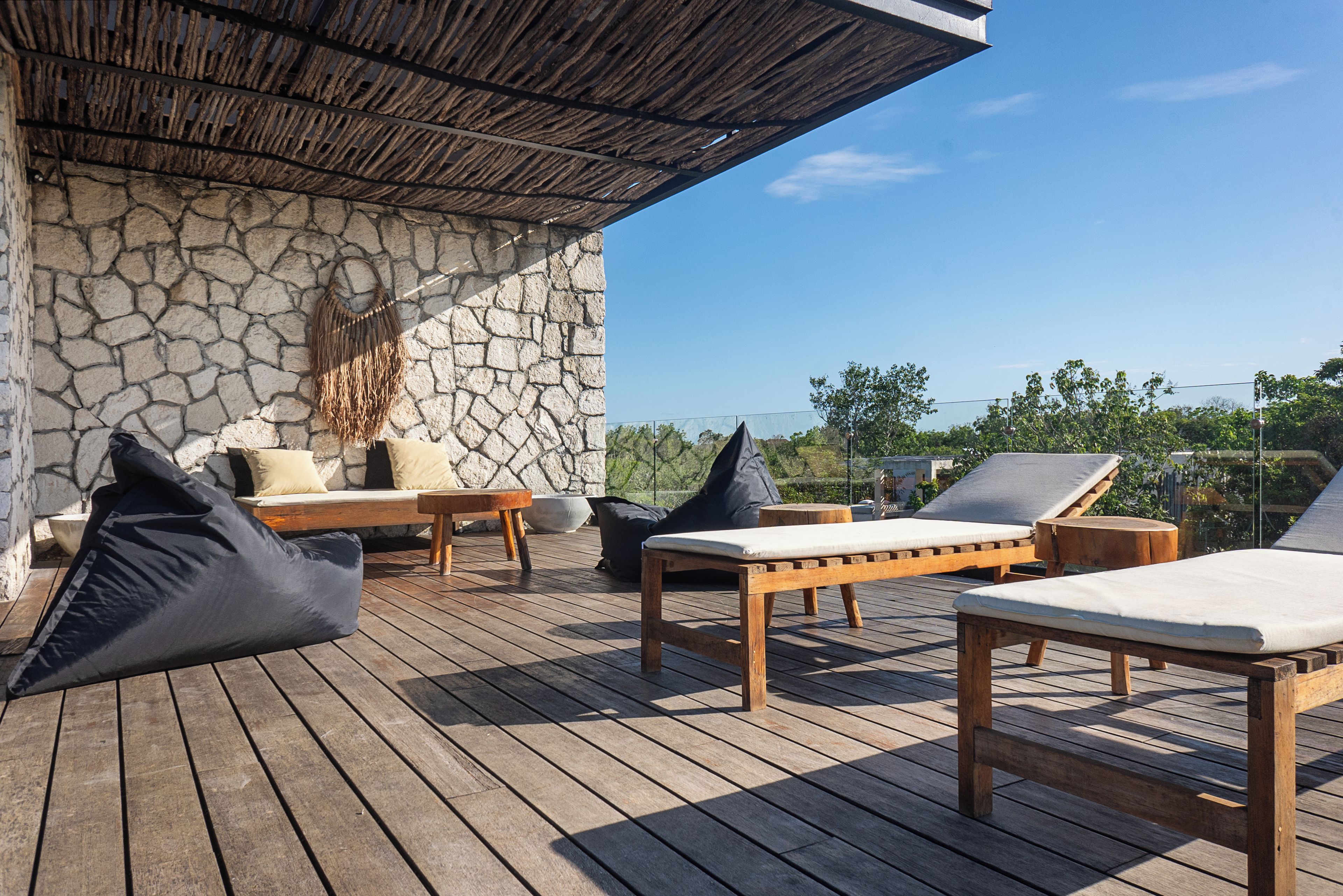 A wooden deck with lounge chairs and a stone wall.