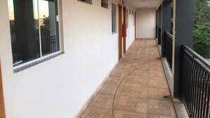 A corridor with large windows, a tiled floor, and a black railing on one side. - Hotel Canoas (Tres Lagoas)