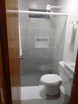 A bathroom with a toilet, a shower enclosure, and a towel rack. - Hotel Canoas (Tres Lagoas)