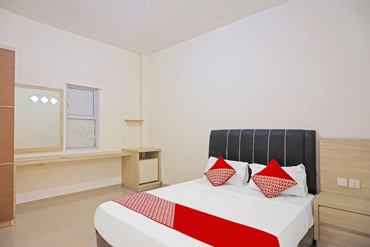 A hotel room with a bed, a nightstand, a small table, and a window.