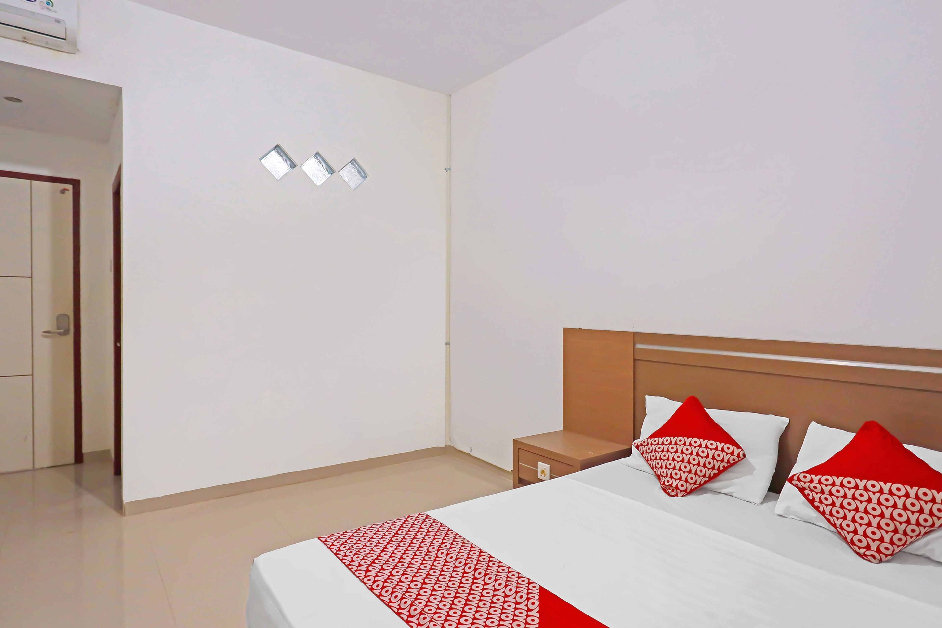 Una habitación de hotel con una cama, dos mesitas de noche y una puerta que da a otra habitación.