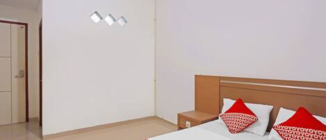 Una habitación de hotel con una cama, dos mesitas de noche y una puerta que da a otra habitación.