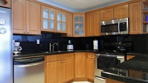 Une cuisine moderne avec des meubles en bois, des appareils électroménagers en acier inoxydable et des plans de travail noirs.
