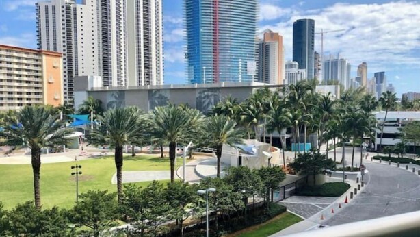 Un quartier urbain moderne, caractérisé par de grands immeubles, des palmiers et un espace public bien aménagé, avec un chemin sinueux et de la verdure.