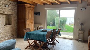 A dining area with a table set for four, wooden chairs, a blue tablecloth, and a stone wall.