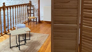 A room with a wooden ceiling, a stone wall, a wooden bench, a table, and a sliding door.