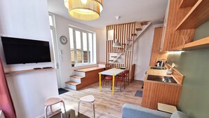Un espace de vie moderne comprenant un téléviseur, un coin repas, une cuisine et un escalier.