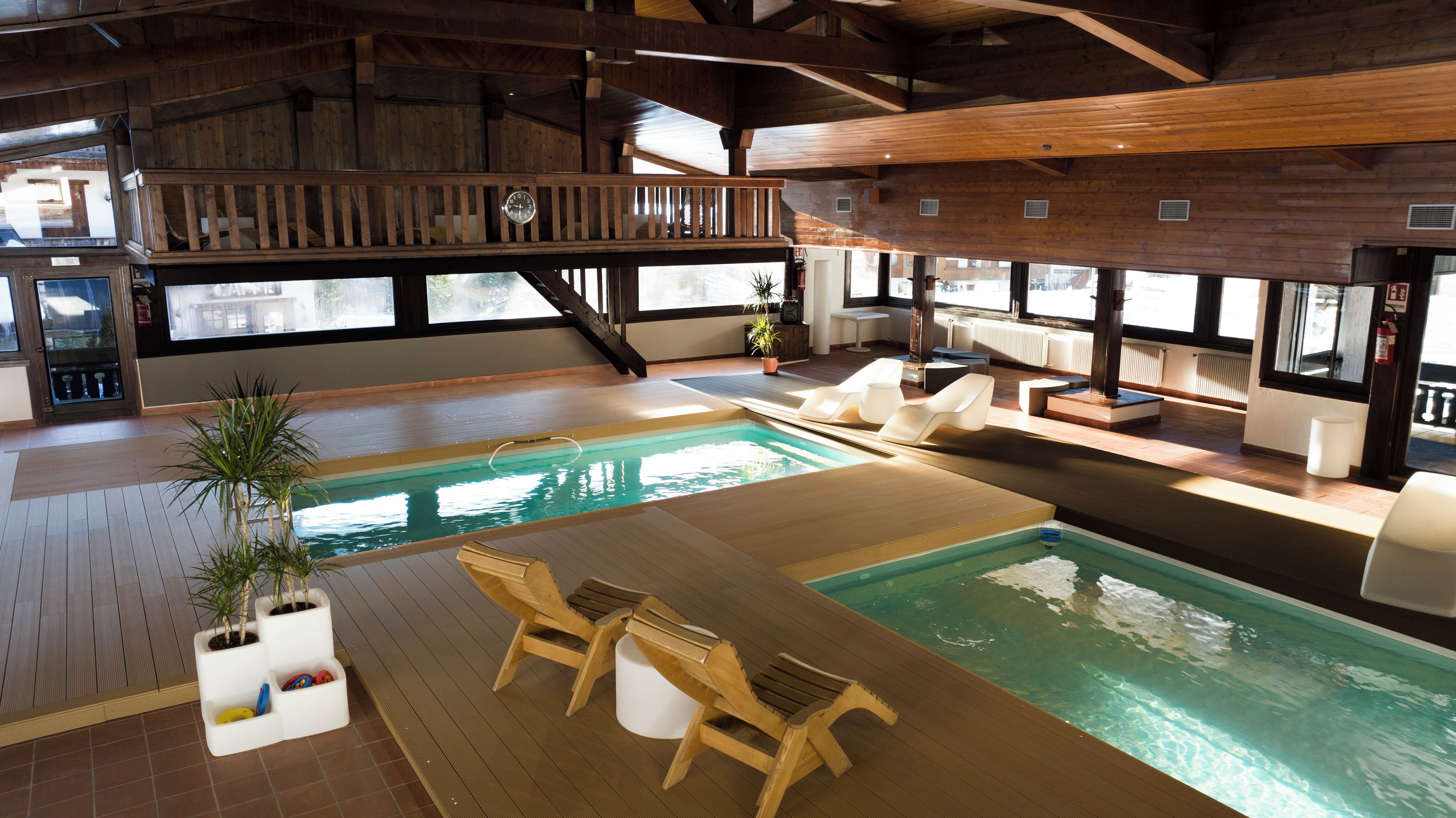 A spacious indoor swimming pool with wooden deck seating and a wooden deck area.