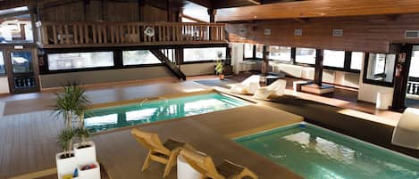 A spacious indoor swimming pool with wooden deck seating and a wooden deck area.