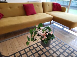 A living room with a sofa and a glass coffee table with a potted plant. - Luxury River View 2-bed Apt, Wifi, Garden, River (Salford)