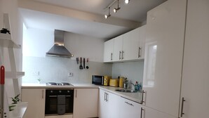 A modern kitchen with white cabinets, a stainless steel range hood, a microwave, and a toaster. - Luxury River View 2-bed Apt, Wifi, Garden, River (Salford)