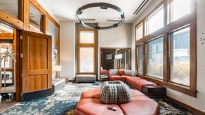 A modern hotel room with a large window, a sofa, a remote control, and a unique circular light fixture.