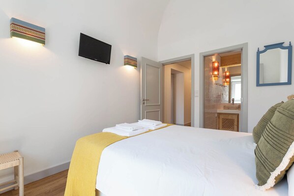 Een hotelkamer met een bed, een televisie, een spiegel en een badkamer zichtbaar door een geopende deur.
