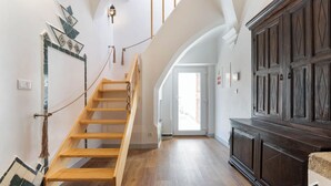 A spacious hallway with a wooden staircase, a dark wooden cabinet, and a tiled wall decoration. - Casa Cordovil Evora (Évora)