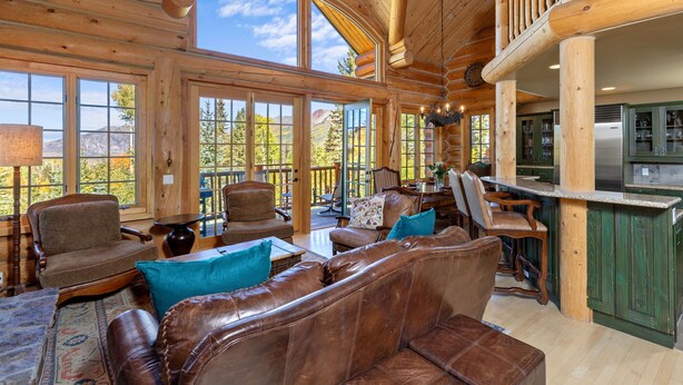 A spacious cabin interior with a large wooden ceiling, a cozy seating area with leather sofas, and a kitchen area with green cabinets. - First Tracks on Sundance - Slope-side Skiing! Views - Private Hot Tub - A/C ! (Mountain Village)