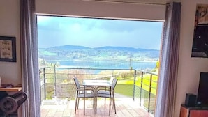 Une chambre dotée d’un jacuzzi, d’un balcon avec une table et des chaises, et offrant une vue sur la campagne.