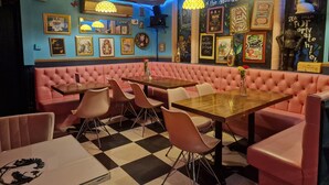 A restaurant interior with pink booths, checkered flooring, and various framed pictures on the walls.