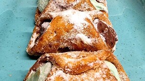 A tray of pastries with powdered sugar and a green filling, served on a blue plate.
