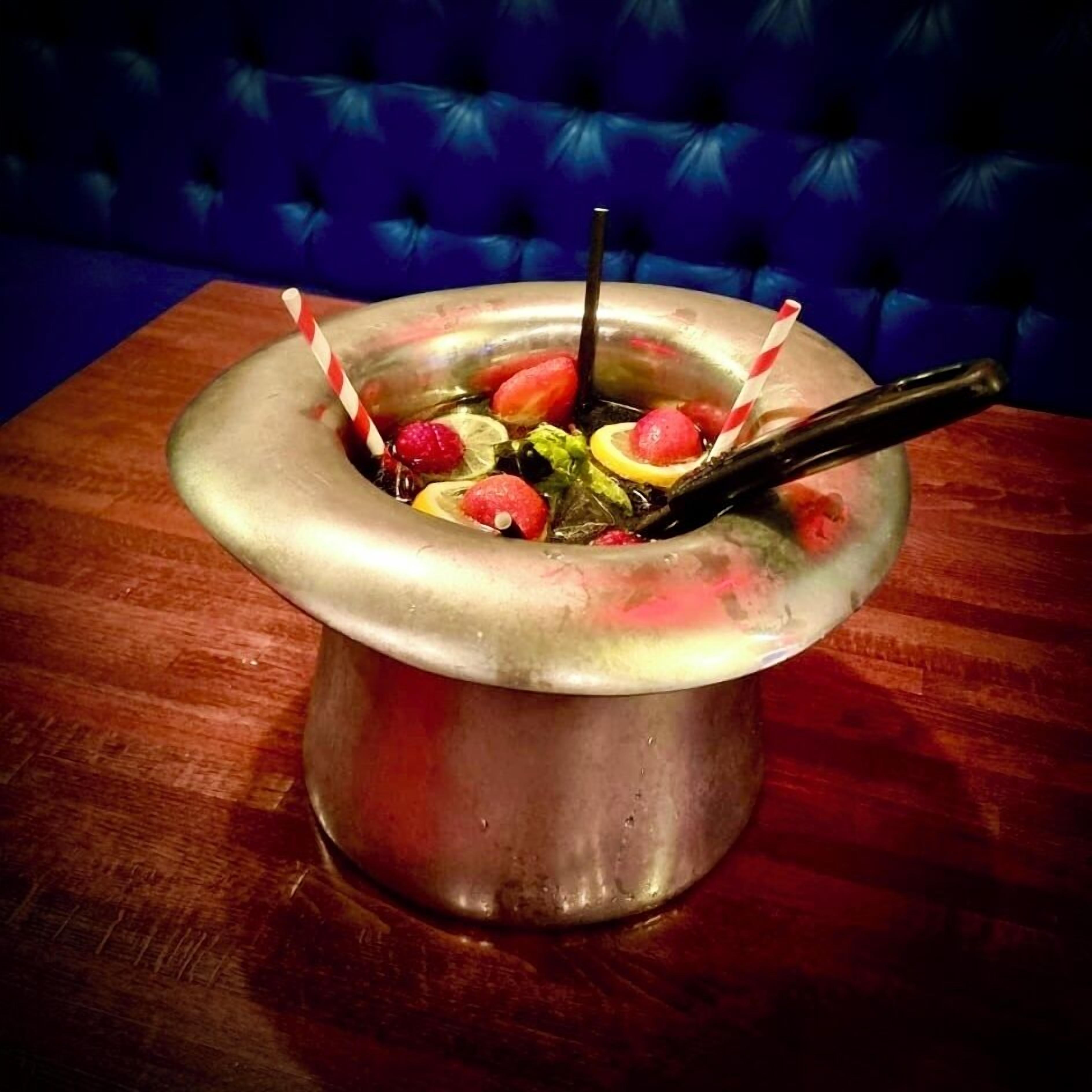 Un bol en métal contenant des fruits et une paille, posé sur une table en bois.