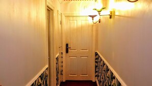 A hallway with a red and white striped ceiling, a light fixture, and a door at the end.