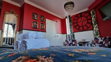 A room with a bed, a large clock, and a mirror.
