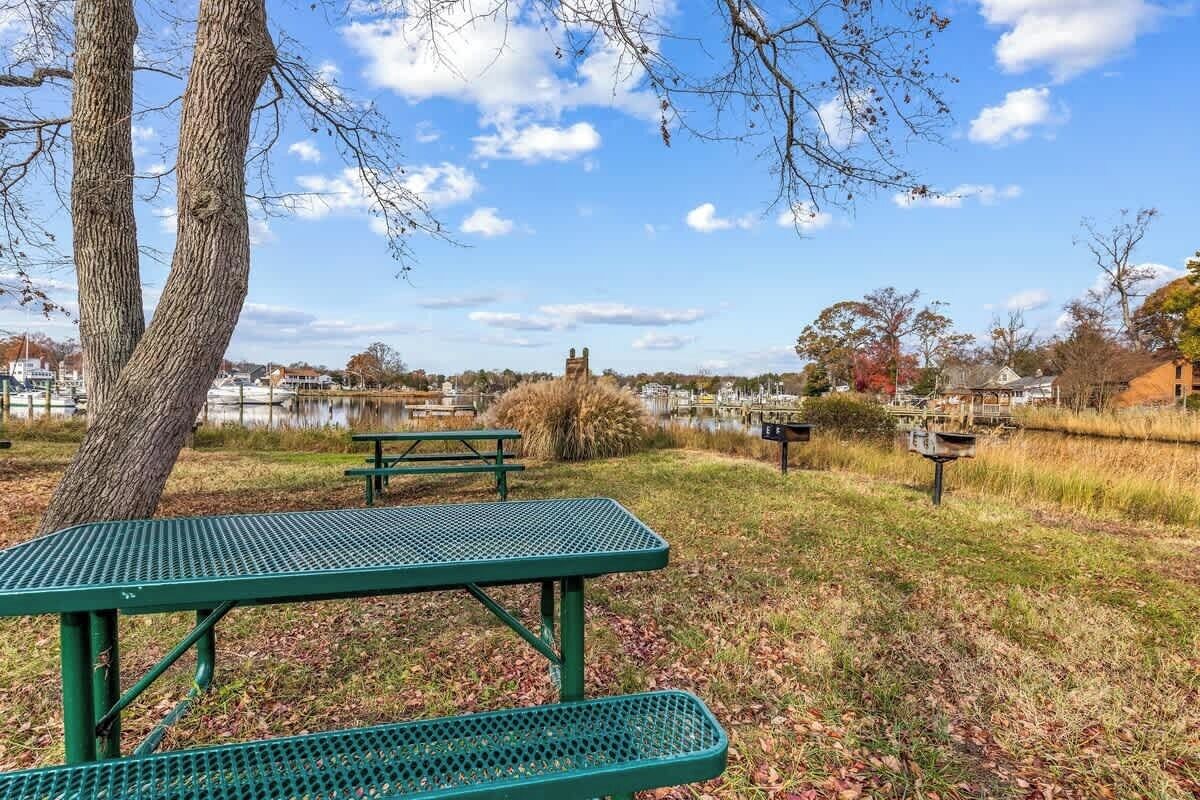 Una mesa de picnic en un parque con un lago y edificios al fondo.