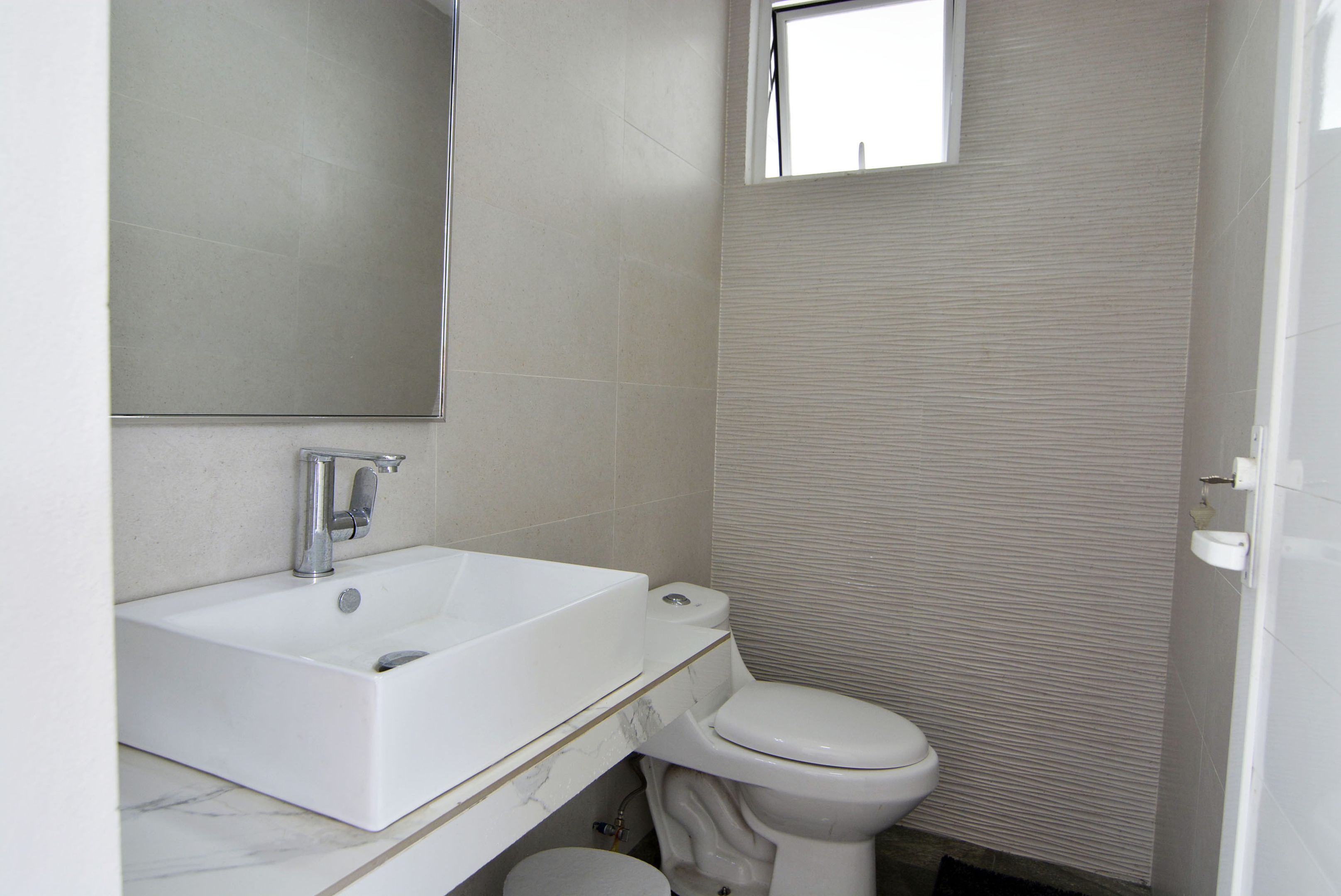 Un baño con lavamanos, espejo y retrete blanco.