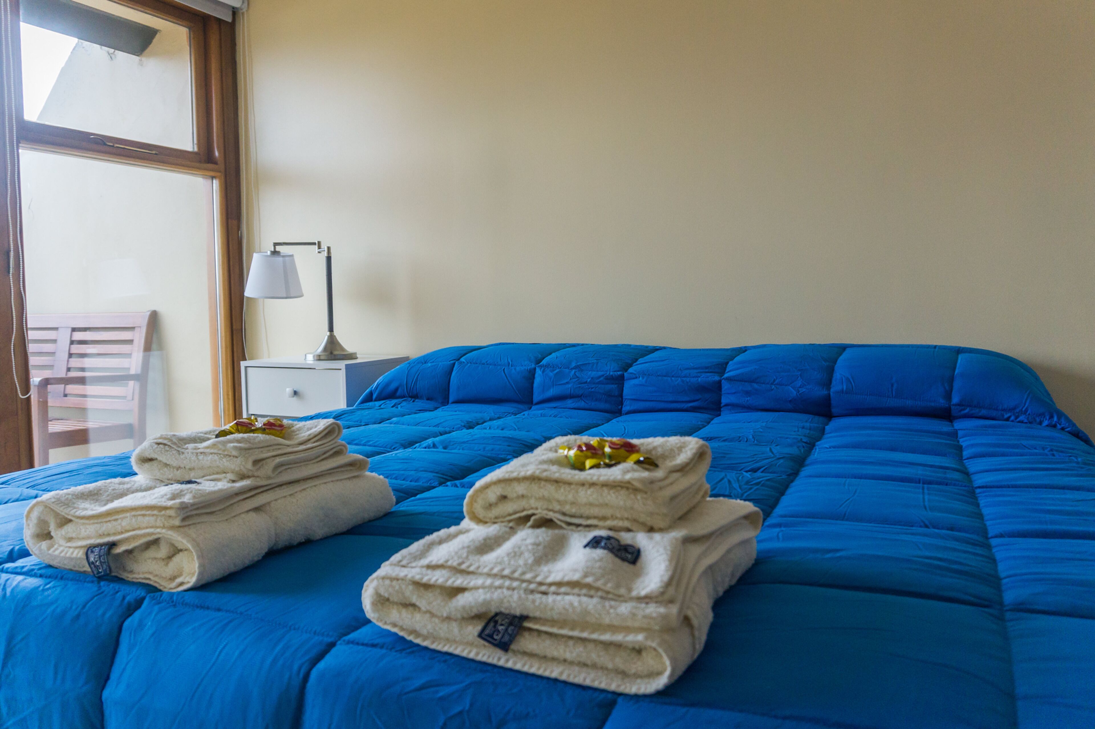 A bed with blue bedding and white towels.