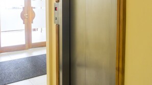 An elevator with a control panel, a door, and a wall with a light switch. - Gente del Sur - Odino (Ushuaia)