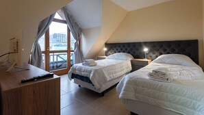 A hotel room with two beds, a desk, and a large window with curtains. - Gente del Sur - Odino (Ushuaia)