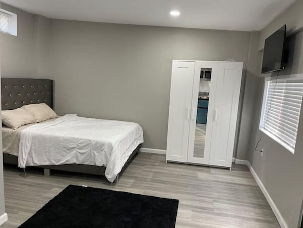 A bedroom with a bed, wardrobe, and a TV on the wall.