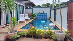 A swimming pool with a tiled wall, surrounded by potted plants and white lounge chairs. - Luxury Private Pool Villa- Ao Nang Krabi  (Tambon Ao Nang)