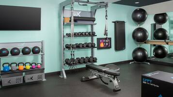 Een sportschool met gewichthefapparatuur, dumbbells, kettlebells en fitnessballen.