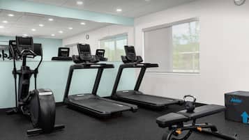 Une salle de sport équipée de tapis de course, d’un appareil elliptique et d’un banc de développé couché.