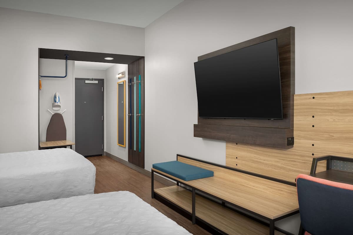 Une chambre d’hôtel avec deux lits, un téléviseur à écran plat, un bureau en bois et une chaise.