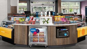 A self-service beverage station with a refrigerated display, a microwave, and a variety of snacks and drinks. - Tru by Hilton Jacksonville Airport I-95 (Jacksonville)