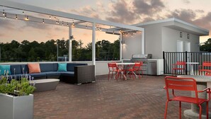 An outdoor patio with a sofa, chairs, and a grill area. - Tru by Hilton Jacksonville Airport I-95 (Jacksonville)