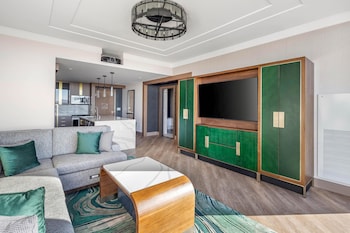 A modern reception area with a wooden reception desk, a digital screen, and a large mural of a mermaid. at Hilton Club Elara Las Vegas
