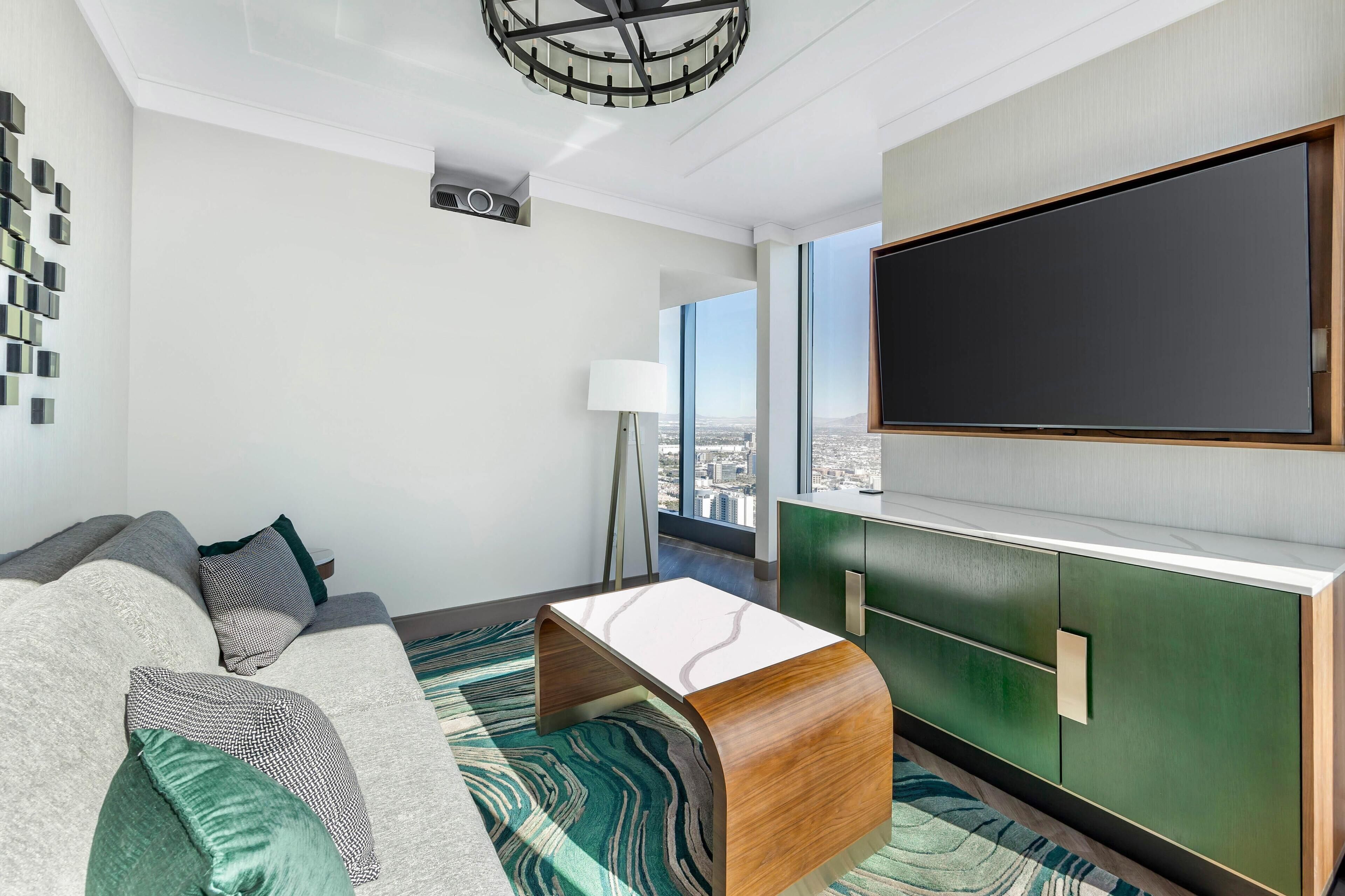 Un salon moderne avec un canapé, une table basse et un grand téléviseur à écran plat fixé sur un meuble vert.