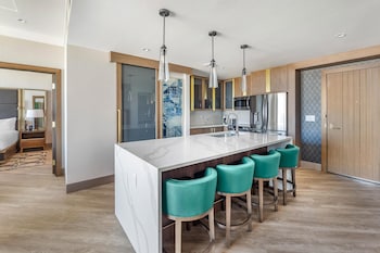 A modern living room with a large sofa, a coffee table, and a dining area with chairs. at Hilton Club Elara Las Vegas