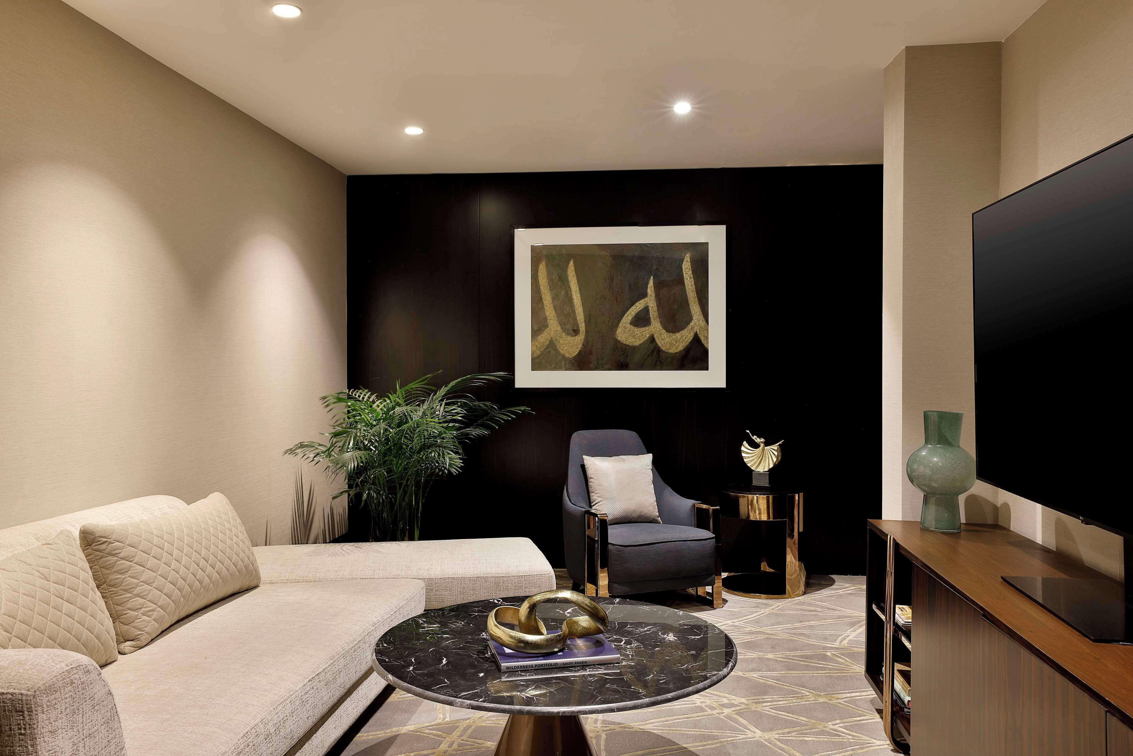 A modern living room with a sofa, a round coffee table, a chair, a television, and a decorative wall piece.