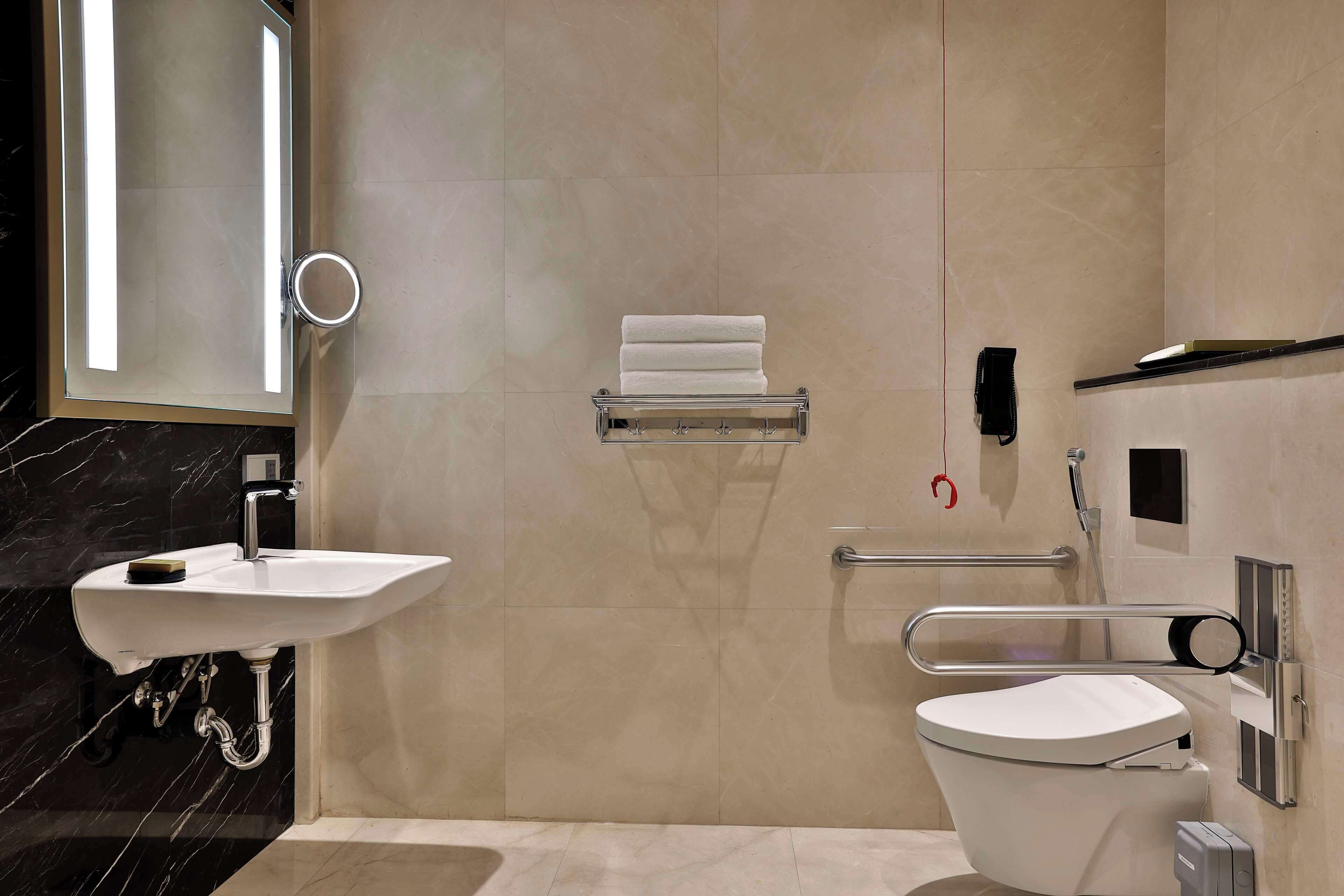 A modern bathroom with a white sink, toilet, and a towel rack.