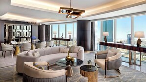 A modern living room with a large sectional sofa, a round coffee table, and a dining area with a glass-top table and chairs. - Hilton Riyadh Olaya (Riyadh)