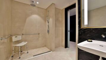 A modern bathroom with a walk-in shower, a white pedestal sink, and a large mirror.