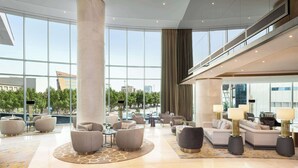 A spacious lobby with modern furniture, large windows, and a view of the cityscape. - Hilton Riyadh Olaya (Riyadh)