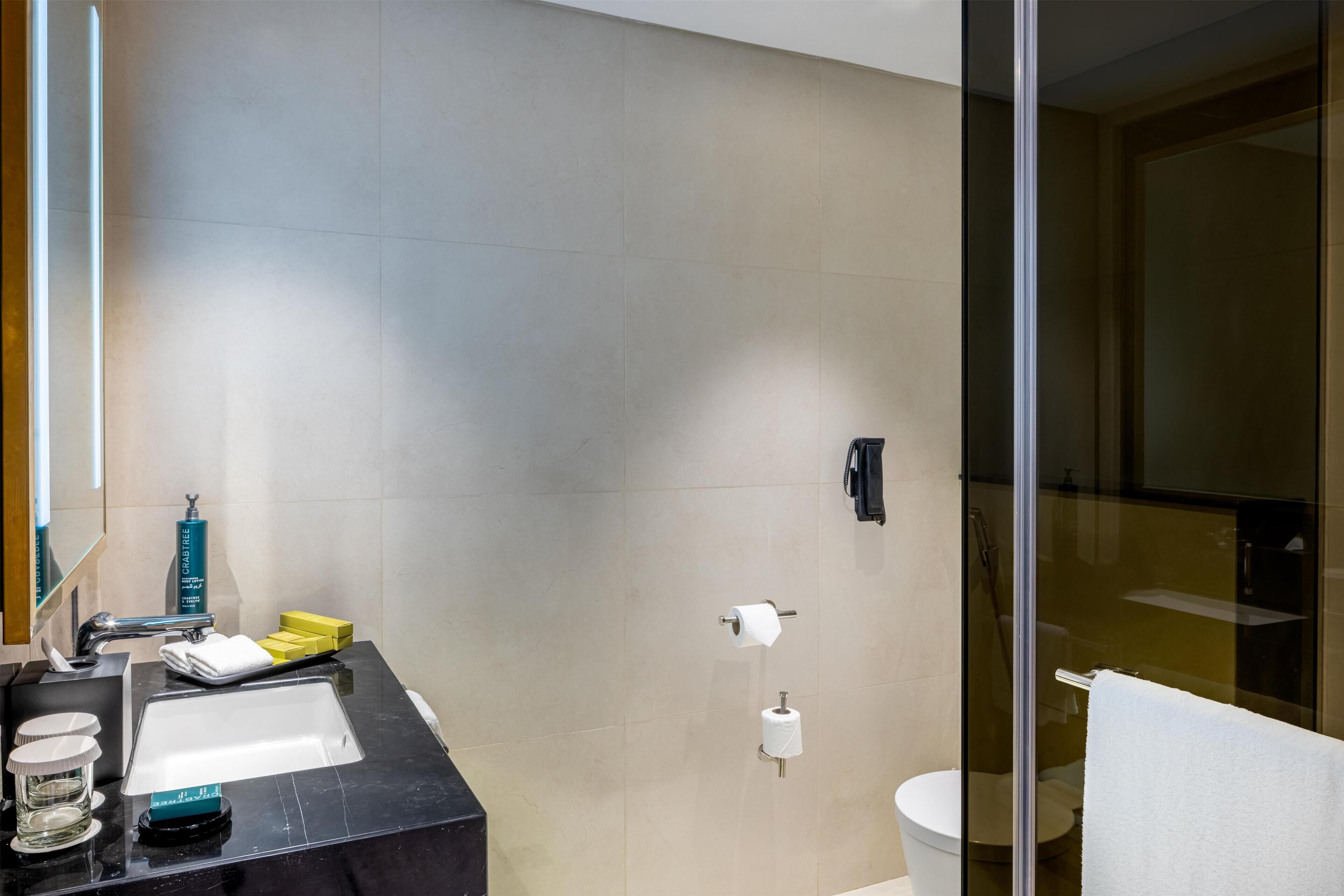 Un baño moderno con encimera negra, cabina de ducha de vidrio y un inodoro.